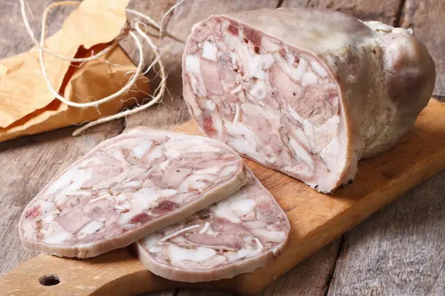 Zabijačková tlačenka na dřevěné desce, řezaná do plátků