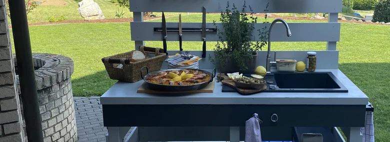 Venkovní kuchyň postavená svépomocí s umyvadlem a noži