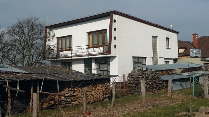 Moderní rodinný dům s přístavbou pro dříví.