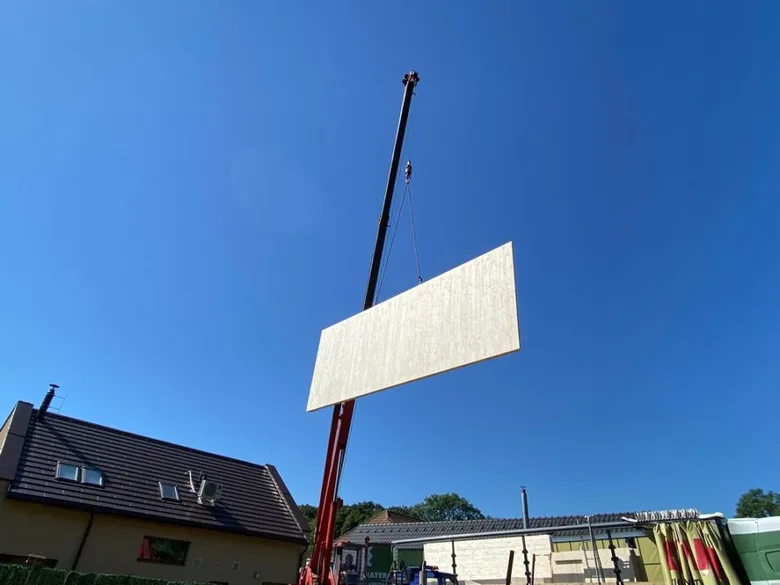 Montáž CLT panely pomocí jeřábu na staveništi.