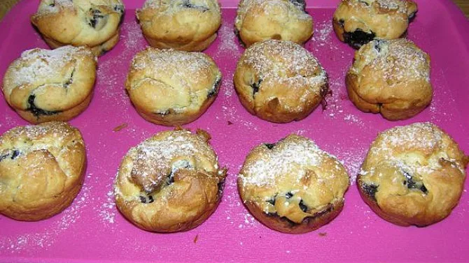 Zlatohnědé bezlepkové muffiny posypané cukrem na růžovém podkladu.