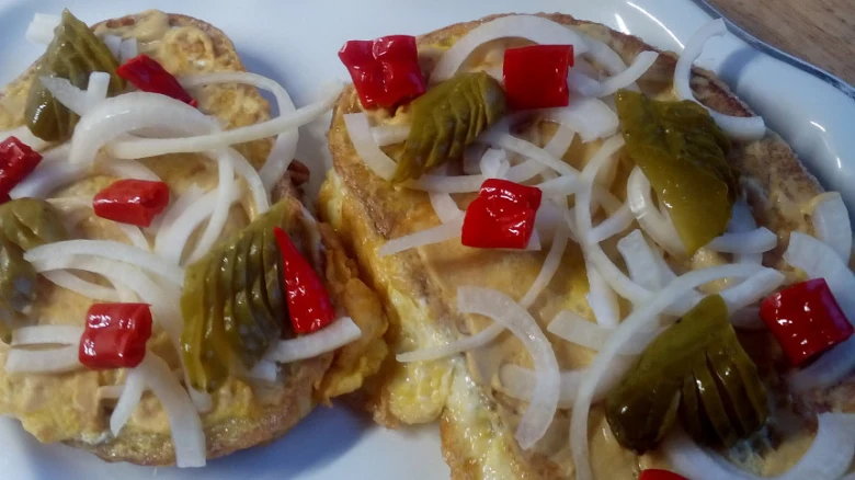 Smaženka s vejci, cibulí, paprikou a okurkou na talíři.