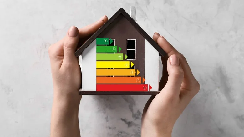 Ruce drží dům s průkazem energetické náročnosti.