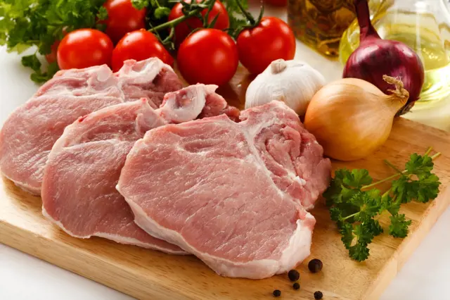 Vepřové plátky s cibulí a kořením na dřevěné desce