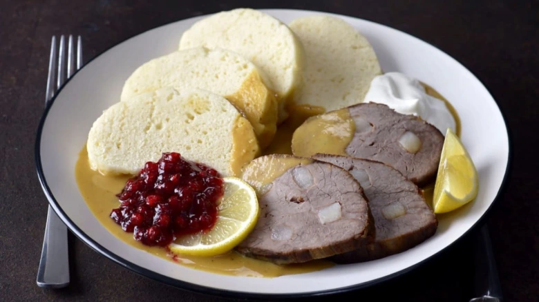Maso s omáčkou a knedlíky na talíři