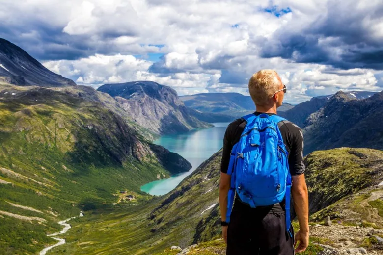 Turista s batohem na pohoří nad fjordem v Norsku