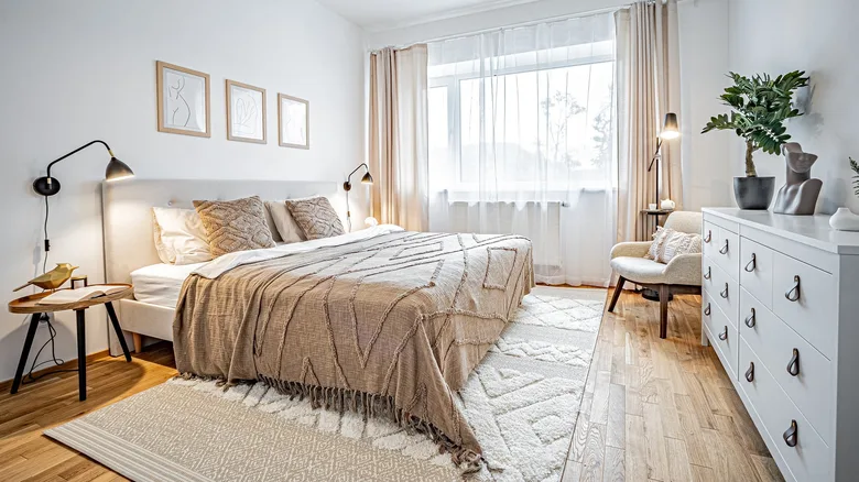 Jasná ložnice s postelí, dřevěnou podlahou a oknem.