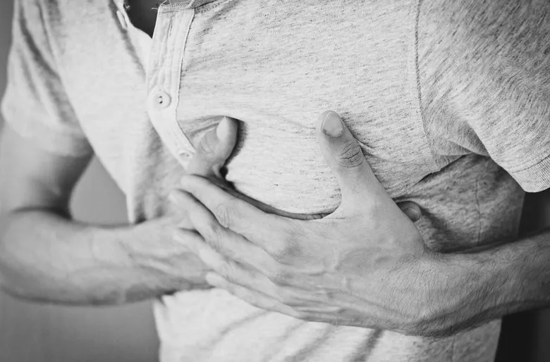Muž drží hrudník v bolesti při podezření na infarkt.
