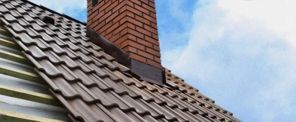Komin s oplechováním na střeše pod modrou oblohou.