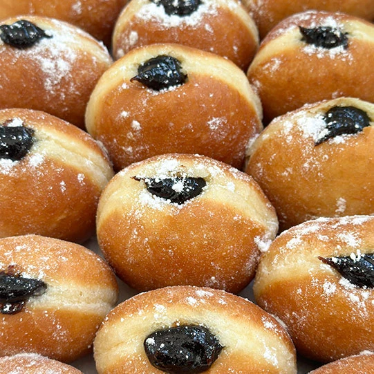 Zlatohnědé koblihy s marmeládou posypané cukrem.