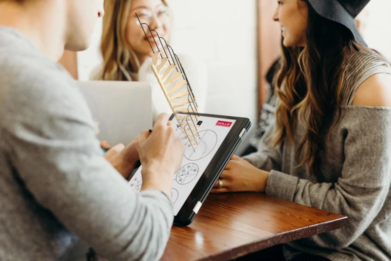 Tři lidé měří výšku schodu pomocí speciálního nástroje na digitálním tabletu.