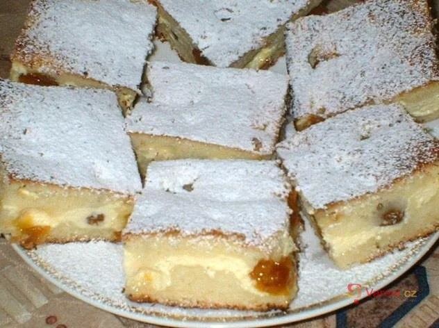 Kus tvarohového koláče posypaný cukrem pudrovým s ovocem uvnitř.