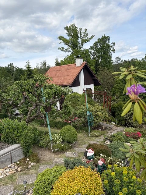 Pohled na krásnou zahradu s domkem v pozadí.