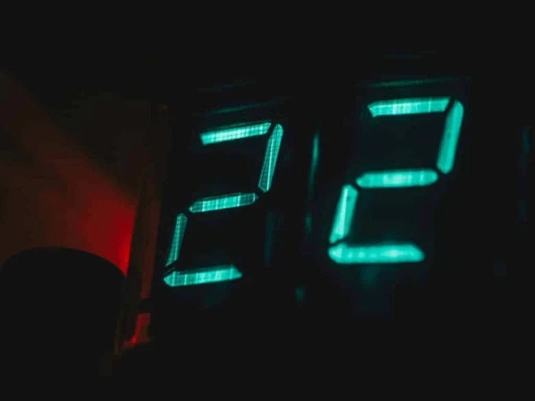 Zelené digitální hodiny ukazující čas 3:2 v tmavém prostředí