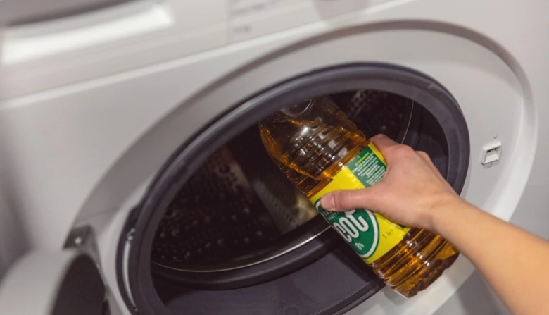 Osoba nalévá žlutou kapalinu do bubnu pračky