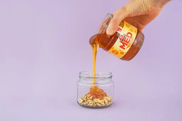 Přelévání medu na ořechy do skleněného dózu