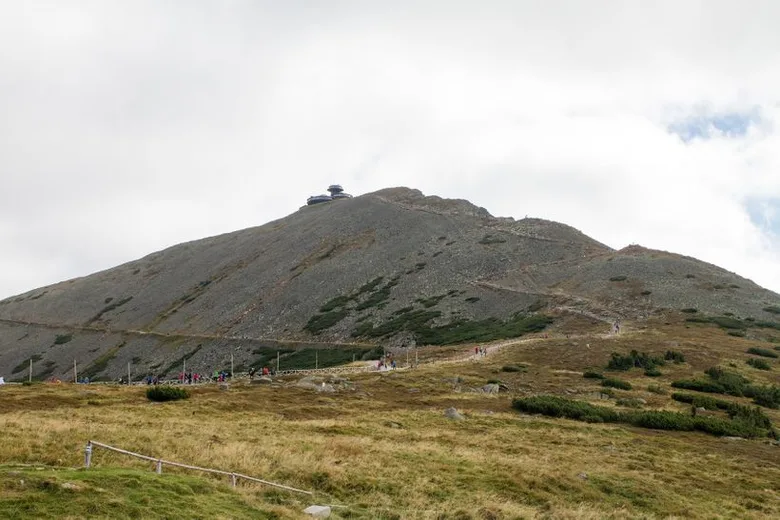 Vrchol pohoří s turistickou trasou a výhledem na krajinu.