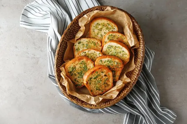 Zlaté topinky s česnekem v košíku na papíře.
