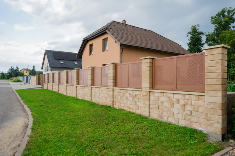 Nový dekorativní plot s kovovou mřížkou před domem.