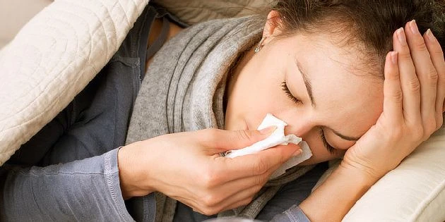 Žena leží v posteli s chřipkou nebo nachlazením.