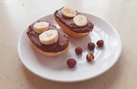 Dvě veganské dezerty s banánem a laskoncem na bílém talíři.
