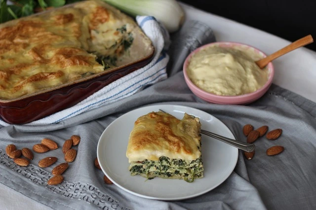 Uzená zeleninová lasagne s kouskem na talíři vedle omáčky.