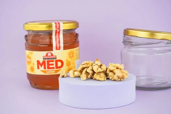 Ořechy v medu – sklenice s medem a ořechy na podstavci
