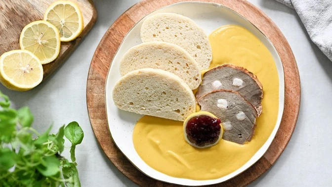 Zabijačková tlačenka na talíři s chlebem a žlutou omáčkou