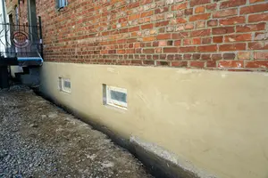 Zdivo s nanesenou vápennou omítkou na spodní části zdi.