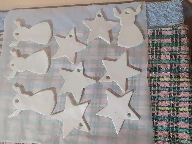 Bílá keramika ve tvaru hvězd a sněhuláků na papíře.