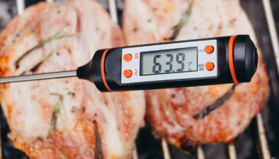 Digitální teploměr měří teplotu masa na grilu.
