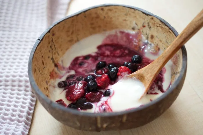 Jogurt s ovocem v kokosové misce na stolu.
