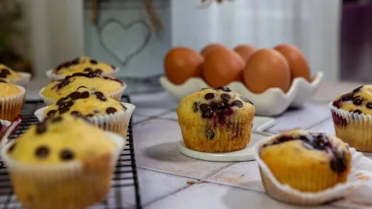 Bezlepkové muffiny s borůvkami vedle vajec na kuchyňské desce.