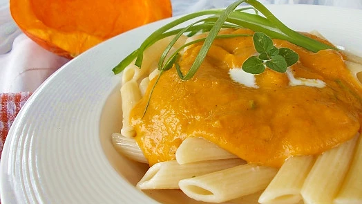 Pasta s dýňovou omáčkou na bílém talíři.