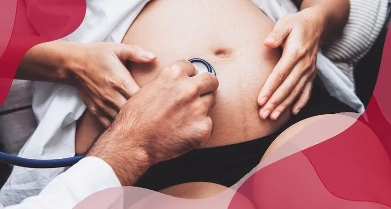 Lékař auskultuje břicho těhotné ženy pomocí fonendoskopu.