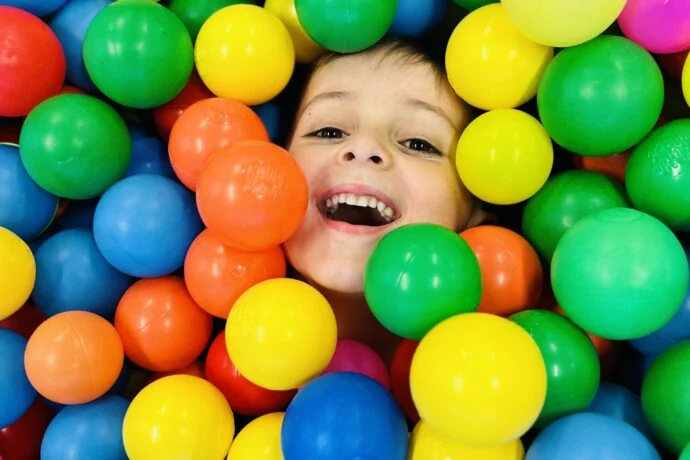 Dětská tvář mezi barevnými hříčkami v bazénu s koulemi.