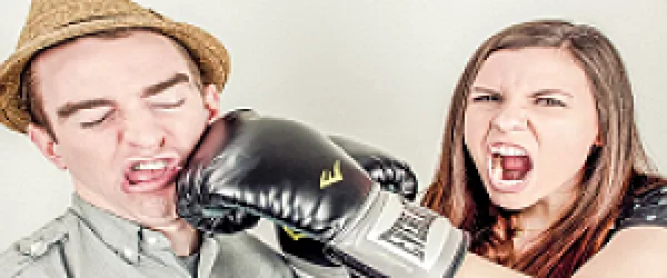 Žena v boxerských rukavicích udeří muže do obličeje.