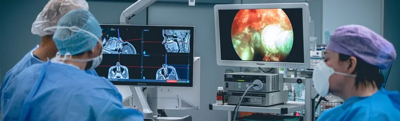 Neurochirurgové pracují v operačním sále u monitorů.