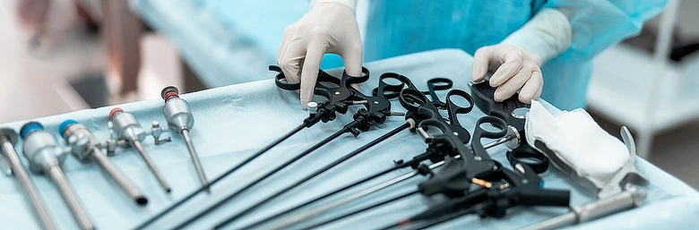 Ruce v rukavicích připravují nástroje pro gynekologickou laparoskopii na sterilním plátně.