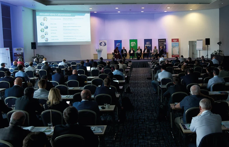 Konference s panelisty na pódiu před publikem v sále.
