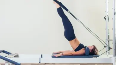 Žena cvičí pilates na přístroji reformér.
