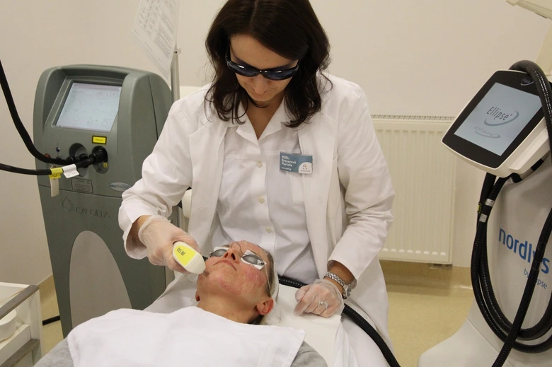 Lékař používá laser k ošetření pigmentových skvrn na obličeji pacienta.