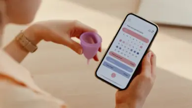Žena drží menstruační šálku a aplikaci pro sledování cyklu.