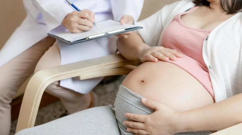 Těhotná žena s lékařem při vyšetření v ordinaci.