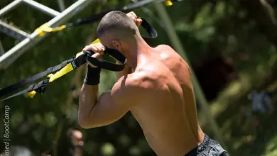 Muž cvičí na bicepsy pomocí TRX pásky venku.