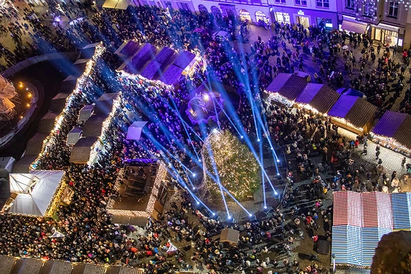 Vánoční trh v Olomouci s davem lidí pod modlými světly.