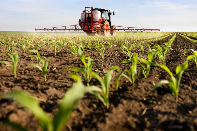 Agricultural tractor spraying crops