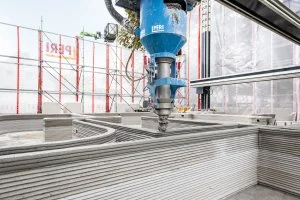 Moderní dům se staví pomocí velkého modrého 3D tiskového robota.