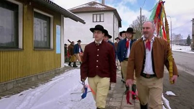 Muži v tradičních kostýmech chodí po sněhu při svátku Barbory.