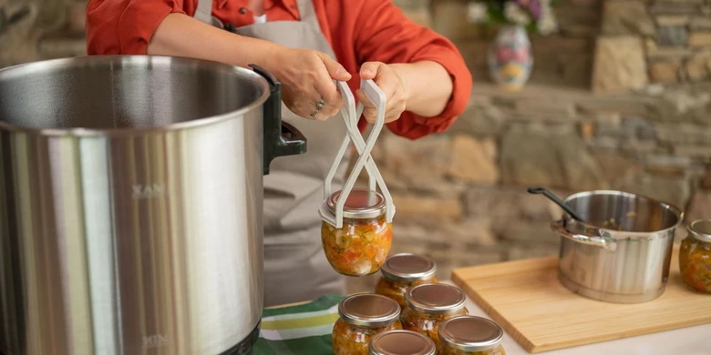 Lid se zavařovaným obsahem vyndává ze sterilizačního hrnce pomocí nástroje.